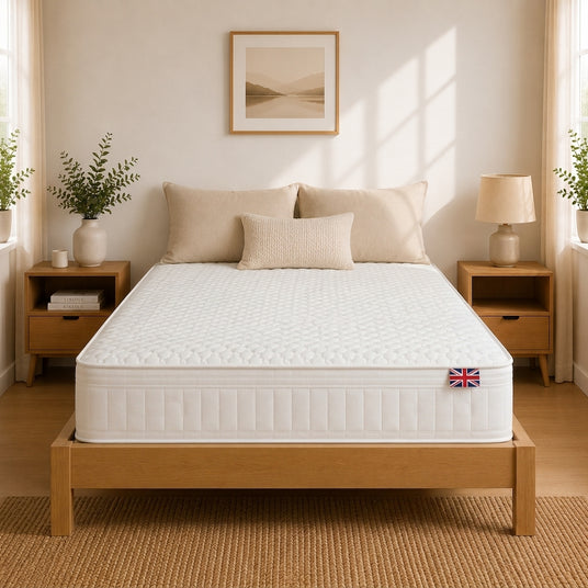 Lola Memory Hybrid mattress on a light wood bed frame in a bright, modern bedroom with beige pillows, wooden nightstands, and soft natural light.